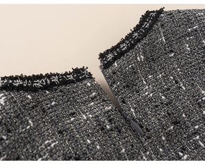 Detail of tweed dress fabric with metallic threads and fringe trim next to zipper