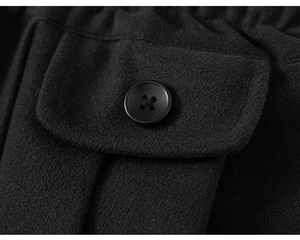 Detail view of black wool pleated skirt pocket with matching button and neat stitching