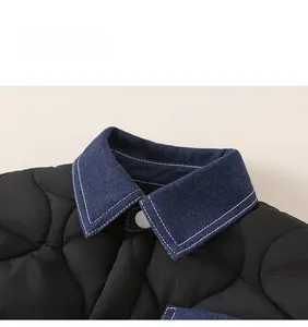Detail of boys' black quilted jacket featuring a blue denim collar with white button