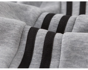 Detail shot of soft grey knit fabric with three black athletic stripes on the sleeve