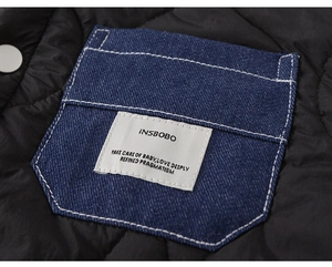 Detail of child jacket showing blue denim pocket with white stitching on black quilted fabric
