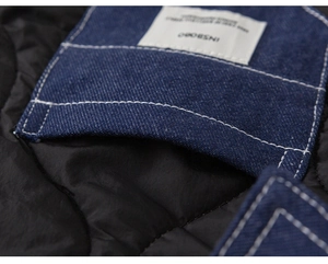 Detailed macro view of diamond-quilted nylon and blue denim collar with white stitching