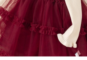 Detail of wine red layered mesh skirt and cream ribbed knit sleeve with ruffle cuffs