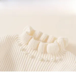 Detail of child knit sweater neckline with delicate ruffles and pearl embellishments