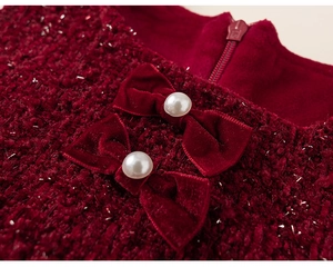 Detail of red tweed dress with velvet bows, faux pearls, and metallic thread weave
