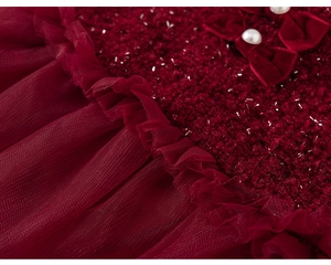 Detailed close-up of wine red tweed fabric with mesh pleats and pearl velvet bow detail