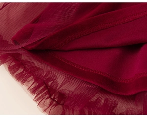 Detailed close-up of dark red tulle layers and precision stitching on winter dress