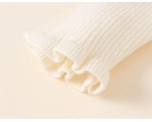 Detail of ruffled cuffs and ribbed knit texture on a cream-colored winter dress