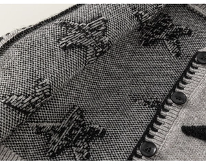 Detail van grijs gebreid vest met sterpatroon en zwarte ronde knopen