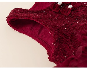 Detail of red tweed dress with velvet bow, shimmering silver silk, and pearl buttons