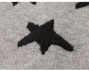 Detail van gebreid vest voor meisjes met een zwart sterpatroon op grijze gebreide stof
