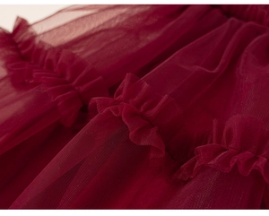 Detailed macro view of tiered burgundy tulle layers and ruffled mesh on a girls dress