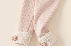 Detail van roze geribbelde meisjeslegging met imitatiebont manchetten en een 3D-strik