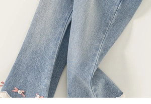 Détail de pantalon en jean évasé pour filles avec nœuds en satin et dentelle blanche