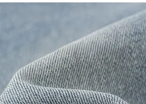 Détail macro du tissu denim bleu clair doux montrant la texture du tissage sergé