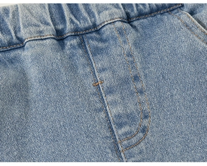 Détail de la taille élastique et de la double couture sur un jean en denim bleu clair