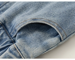 Gros plan sur le denim bleu clair avec des coutures orange contrastées sur la poche