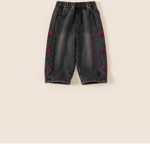 Detailed view of girls' charcoal jeans with red bow embroidery and elastic waist