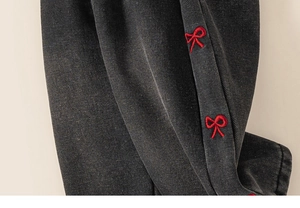 Detail of red bow embroidery on washed black denim fabric for girls' fashion jeans
