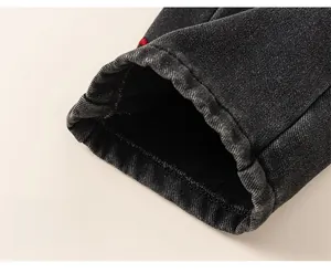 Close-up of wide denim leg opening with red embroidery and high-quality stitching