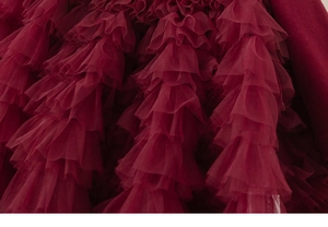 Détail macro des plis de tulle bordeaux multicouches sur une jupe de robe de princesse