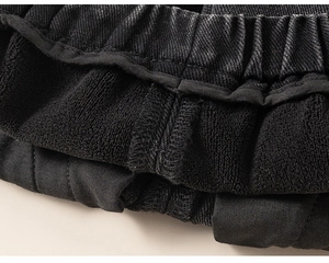 Macro detail of kids black denim jeans showing terry lining and elastic waist stitching