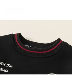 Détail du sweat-shirt noir pour enfant avec broderie blanche et col à rayures rouges
