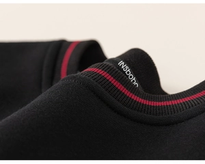 Gros plan du col côtelé avec détail de rayure rouge sur sweat-shirt noir pour garçons
