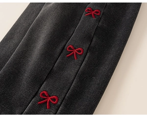 Close-up of dark grey denim fabric featuring three red embroidered bowknot details