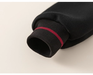 Gros plan du poignet côtelé noir avec rayure rouge sur un sweat-shirt pour garçon