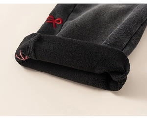 Detail of girls' denim jeans showing warm fleece lining and red bow embroidery design