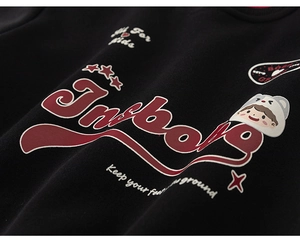 Détail macro d'un sweat-shirt noir enfant avec texte rouge et écusson de dessin animé