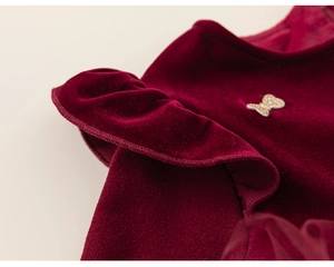Vue détaillée du tissu en velours bordeaux avec volants et nœud doré scintillant pour enfant