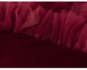 Gros plan détaillé du velours rouge foncé et du tulle en couches sur une robe de fille