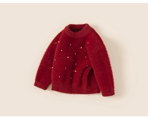 Detailed macro view of girls' red knit sweater with velvet texture and pearl bow accents