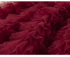 Gros plan détaillé des volants en tulle bordeaux superposés d'une robe de princesse