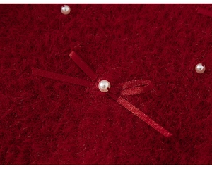 Close-up of fluffy red knit fabric with a silk bow and decorative white pearls