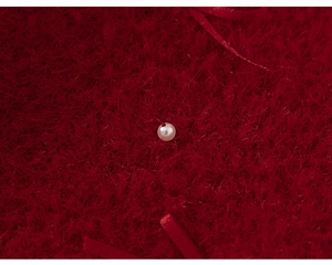 Macro detail of red faux fur knitwear featuring a white pearl bead accent on fabric