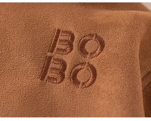 Detailed close-up of BO BO letter embroidery on dark brown suede winter coat fabric