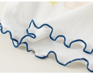 Detailed macro view of cream-colored ribbed fabric with blue lettuce edge on baby shirt