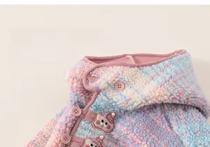 Detail view of pink and blue fleece texture with cute cartoon patch and pearl accents
