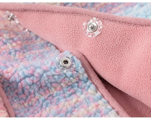 Detail of soft rainbow sherpa fleece fabric with a pink snap button closure for girls