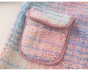 Detailed close-up of rainbow plush fleece fabric and flap pocket on girl's winter jacket