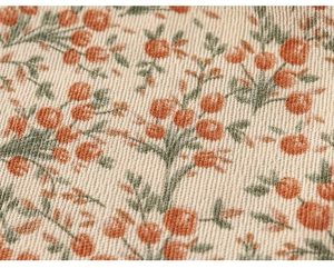 Vue macro d'un tissu beige à fleurs avec des fruits orange et un motif de feuilles vertes