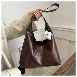 Close-up of brown textured leather tote bag with fashion label and plush star charm detail