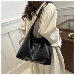 Model wearing a large black minimalist shoulder bag with soft leather texture