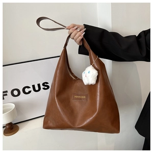 Detail of a brown PU leather shoulder bag with a white star plush charm and golden logo