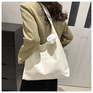 Detail of cream large tote bag with FASHION & BAGS label and plush bear charm