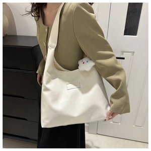 Detail of off-white PU leather hobo bag featuring a decorative plush cloud pendant