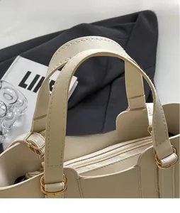 Dettaglio della borsa in pelle crema con doppi manici e anelli metallici dorati